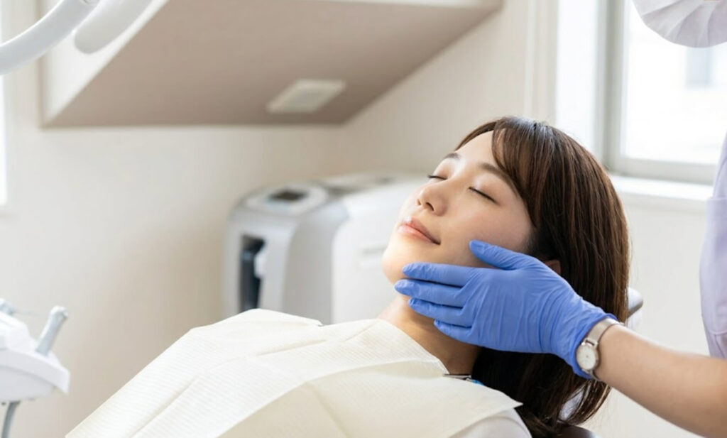 歯科医院で顎を支えられ、リラックスした状態で処置を待つ日本人女性の様子。