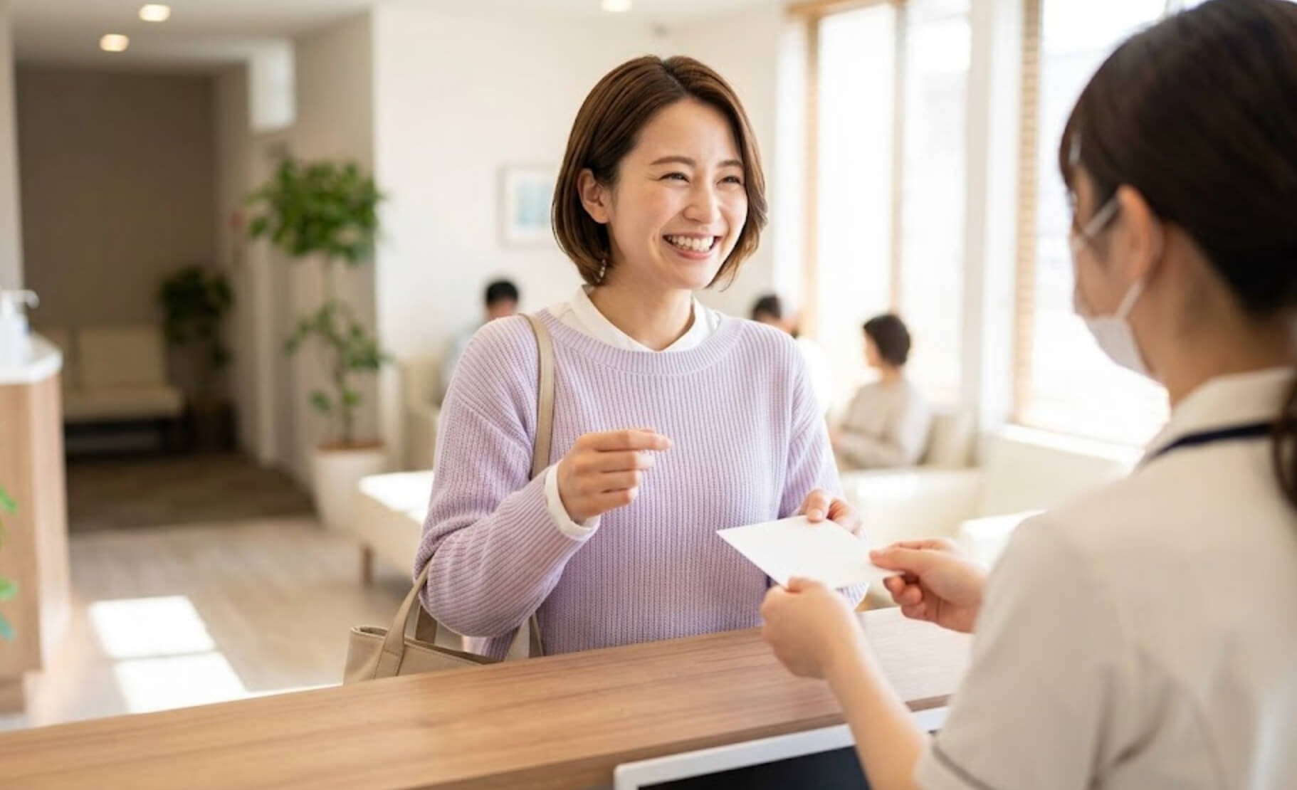 相談後に安心した表情で、スタッフから予約票を受け取る日本人女性