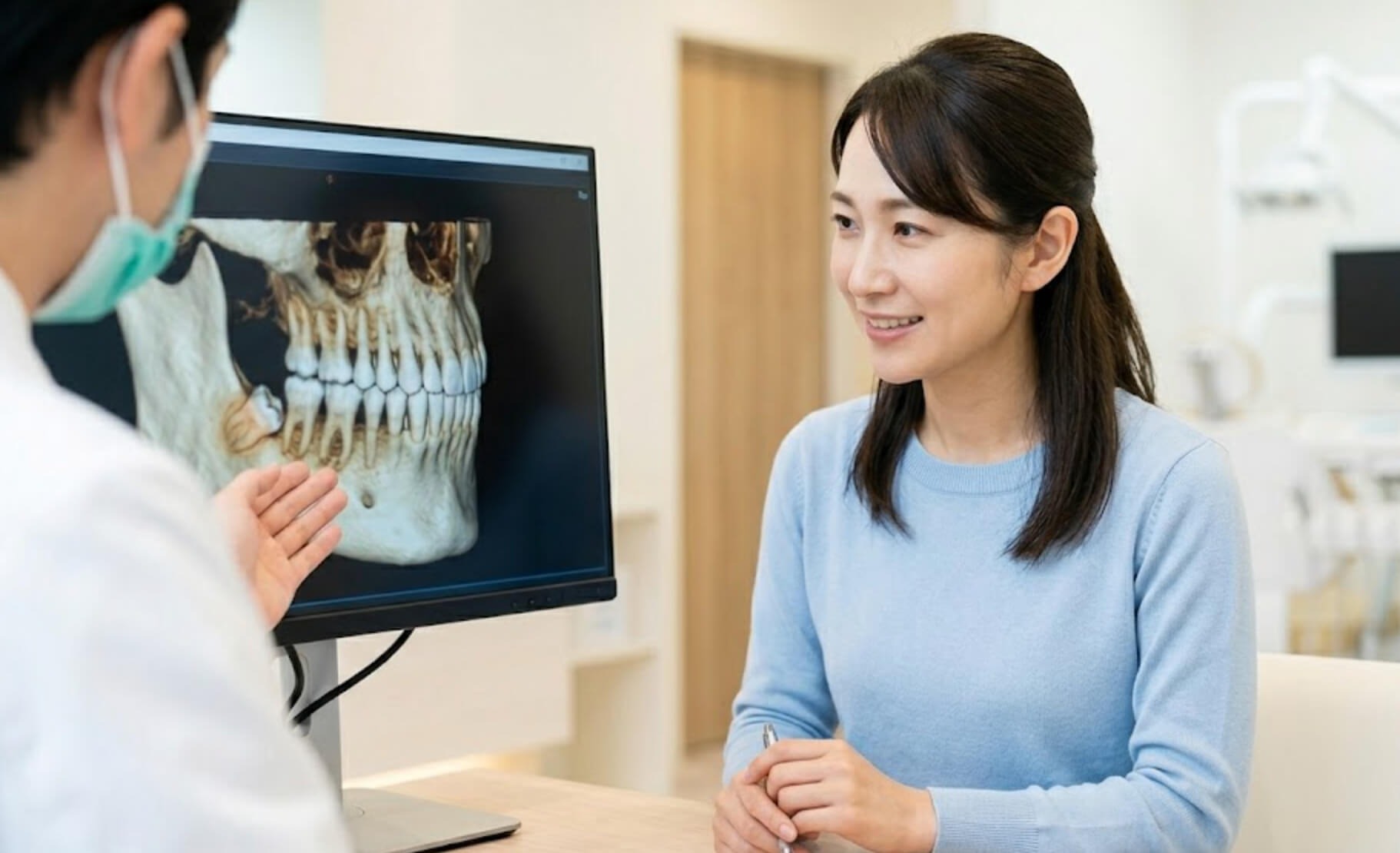 口腔外科への紹介の必要性をCT画像で説明され、安堵する日本人女性